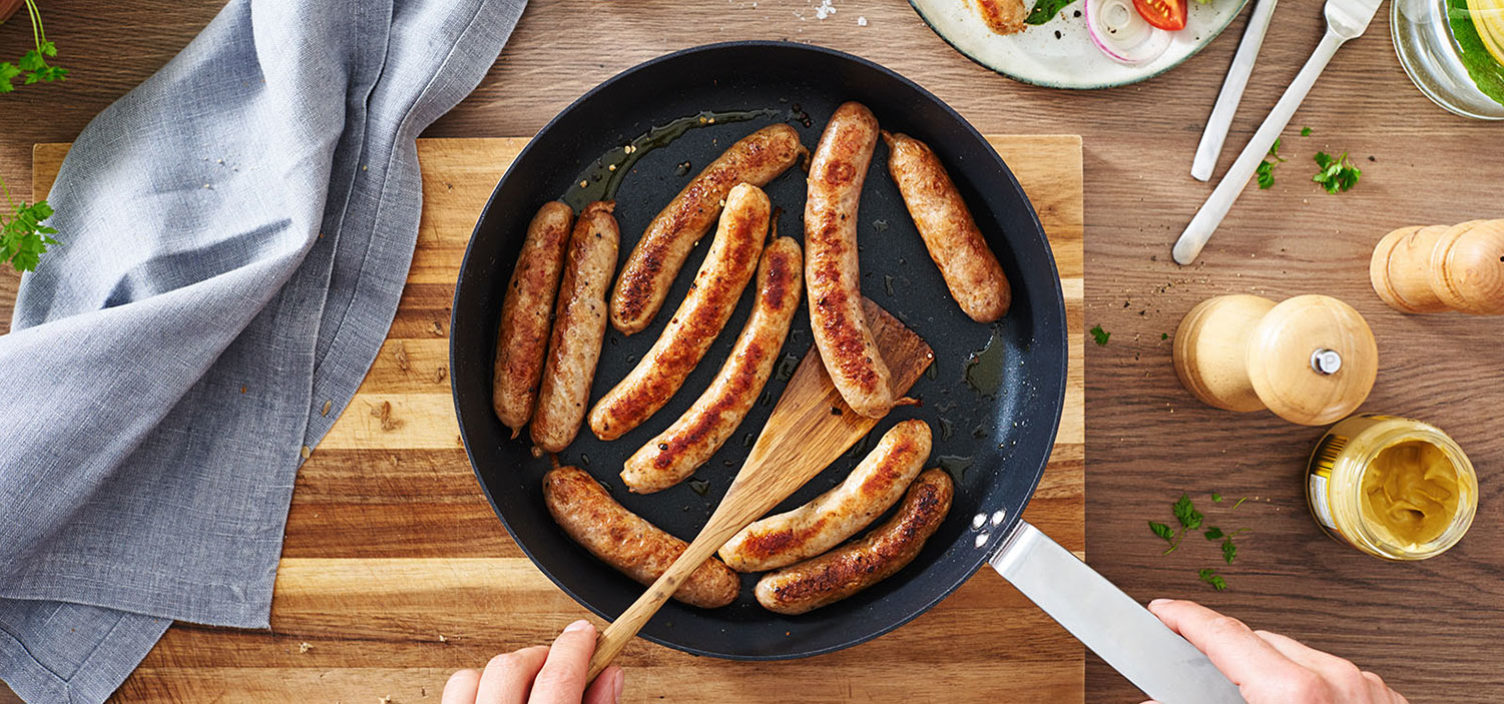 selbstgemachte Bratwurst in Bratpfanne auf Holztisch