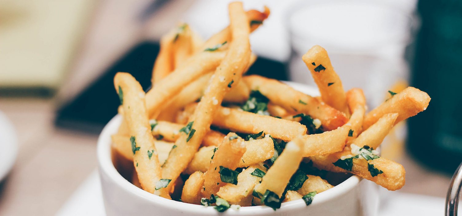 Pommes mit Kräutern in einer weißen Keramikschüssel.