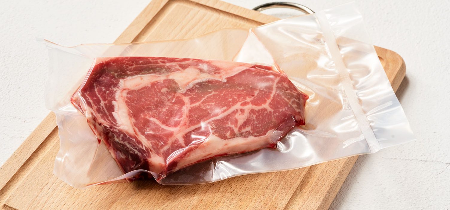 vakuumverpacktes Fleisch auf einem Holzbrett